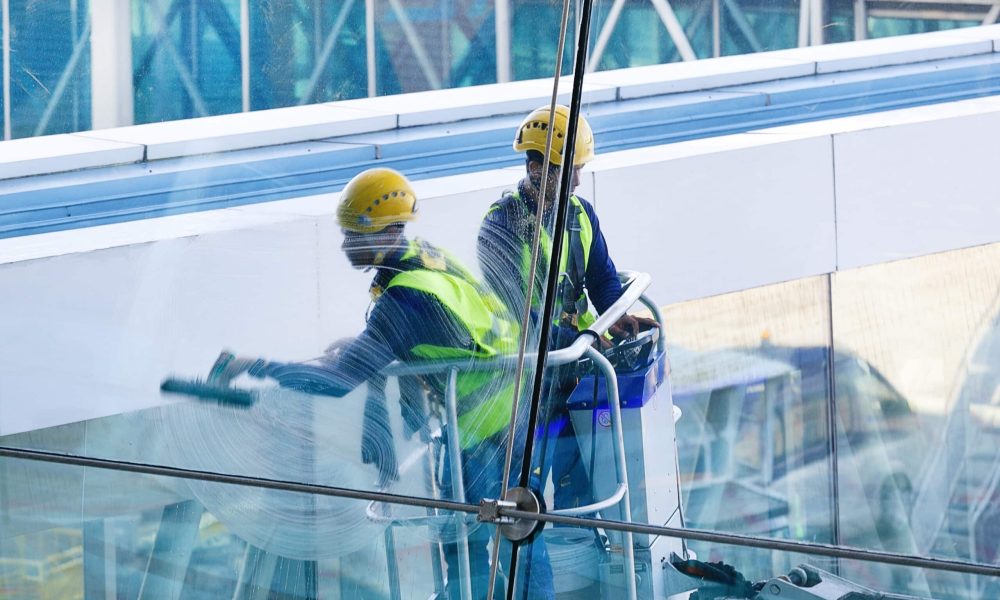 Men Cleaning Windows. Two workers washing windows of the modern business building.